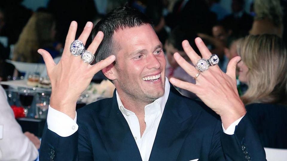 (Brookline, MA, 0/14/15) New England quarterback Tom Brady holds his hands with all four of his Super Bowl rings during a ceremony on Sunday, June 14, 2015. Photo courtesy of the New England Patriots